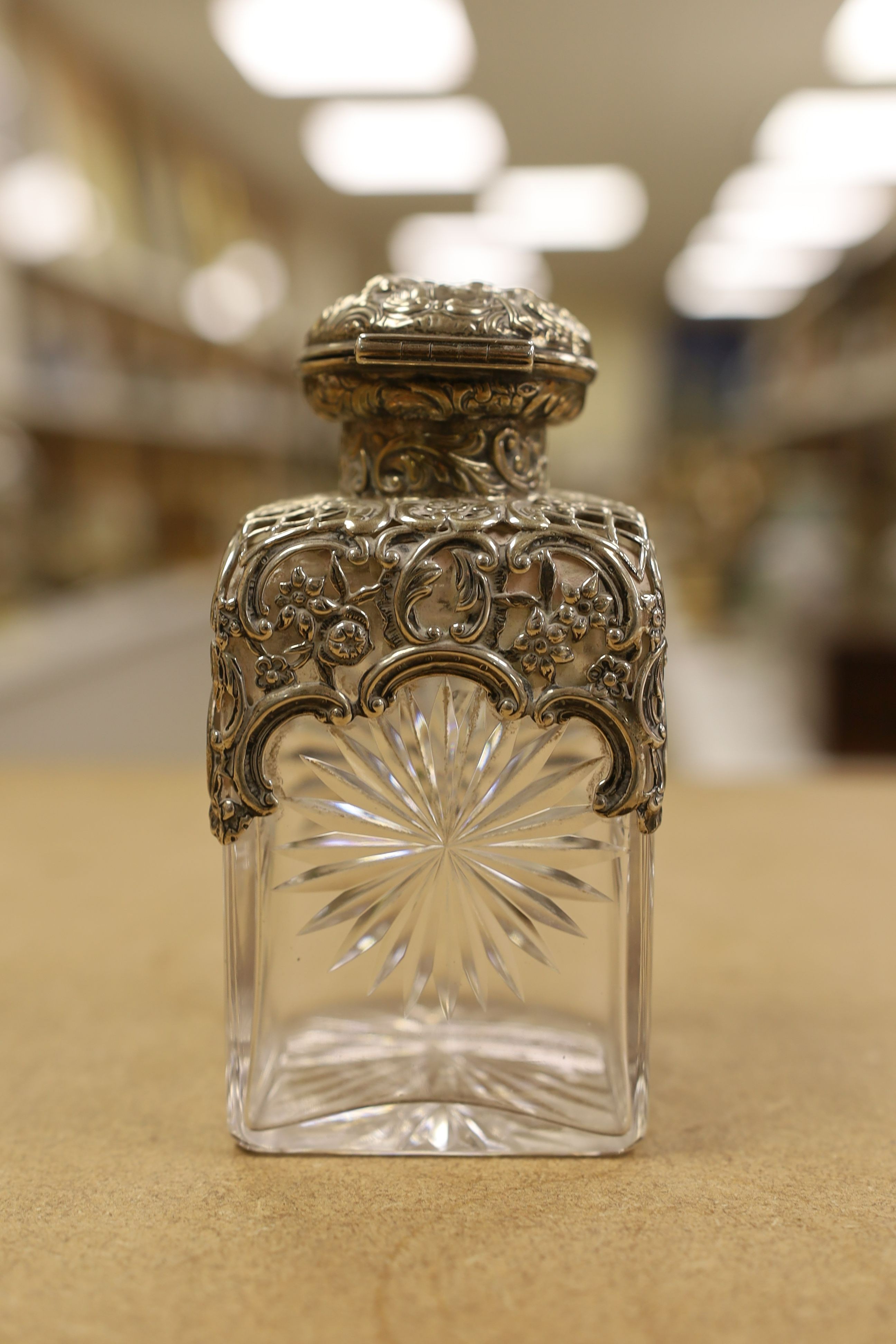 A pair of late Victorian repousse silver mounted cut glass scent bottles with stoppers, William Comyns, London, 1898, height 14.3cm.